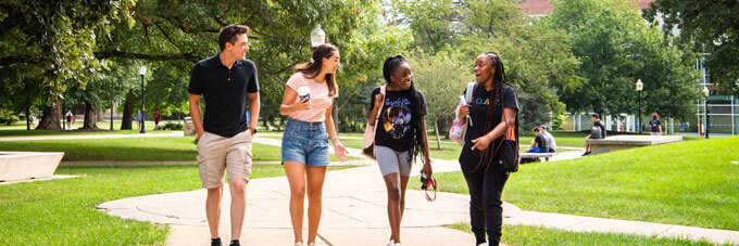 Four students walk across the quad together.